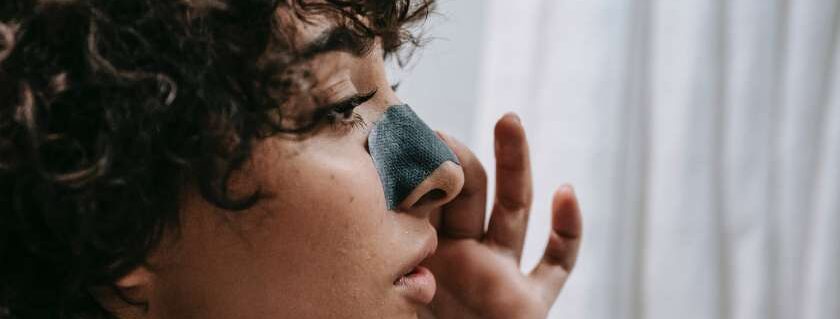 woman with curly hair applying nose strip