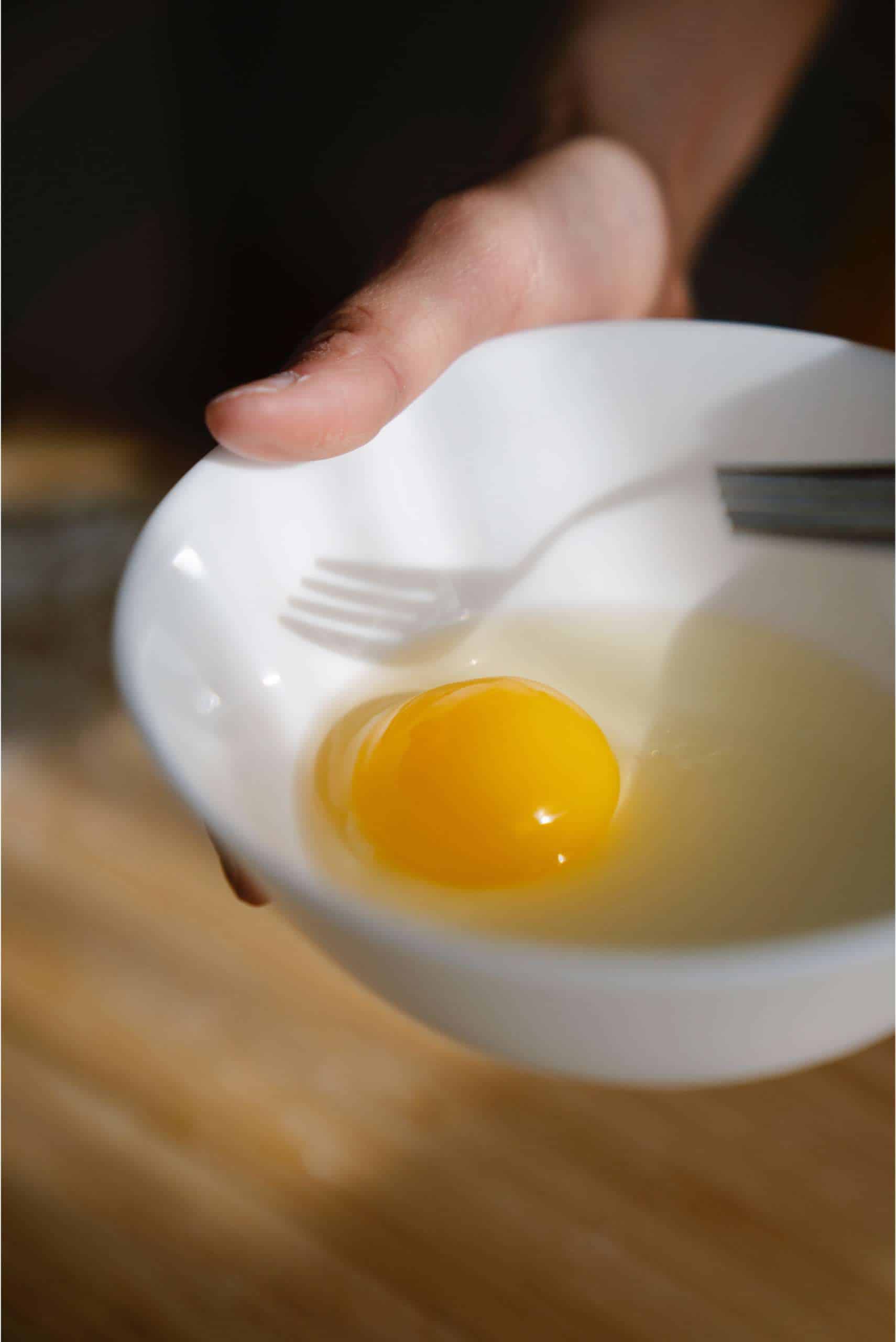 raw egg in white bowl