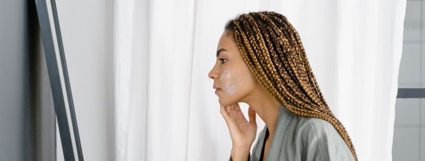 woman with braided hair applies exfoliating mask