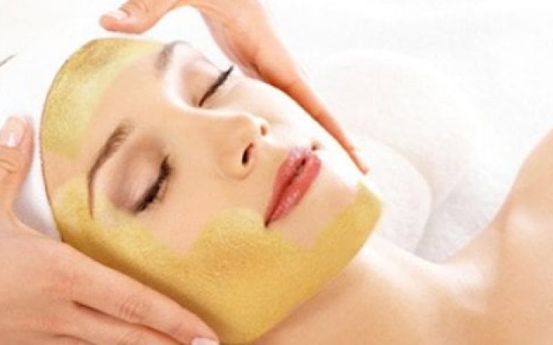 Woman getting facial massage while having gold cream on her face